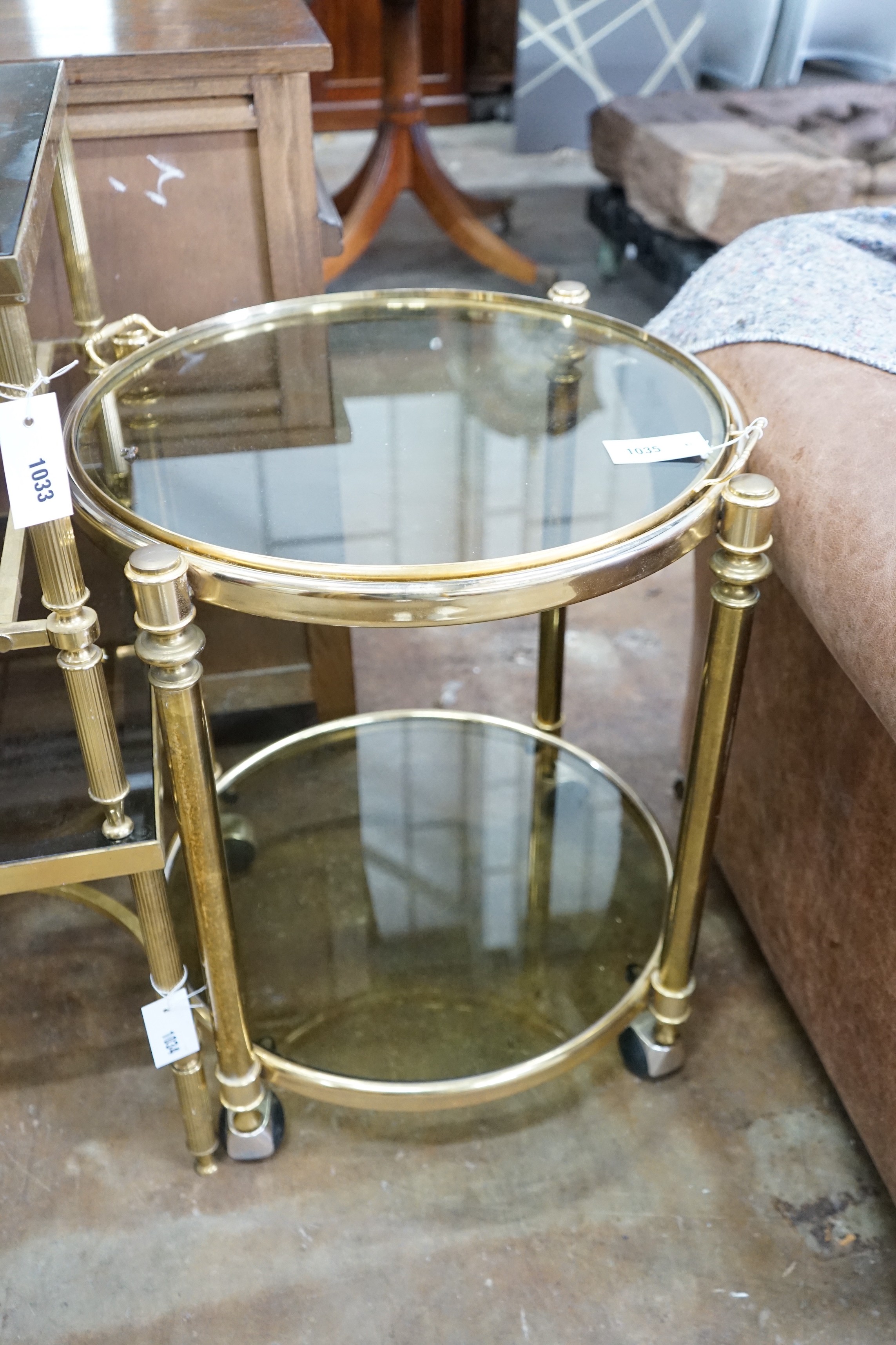 A circular smoked glass and brass tray top two tier occasional table, diameter 57cm, height 64cm